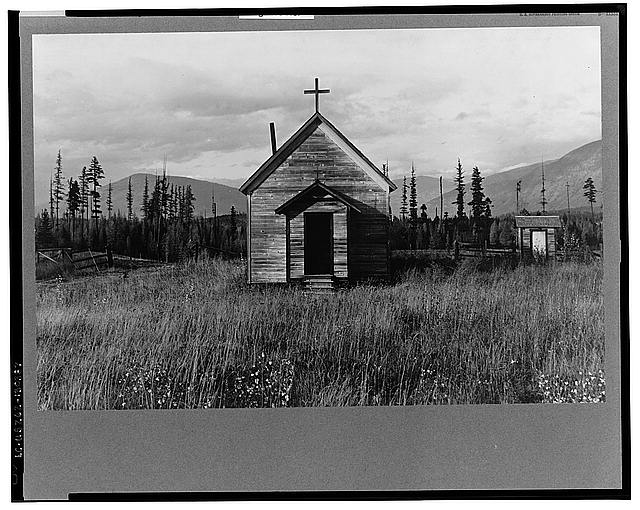 Small abandoned church; few conifers, mountains in background