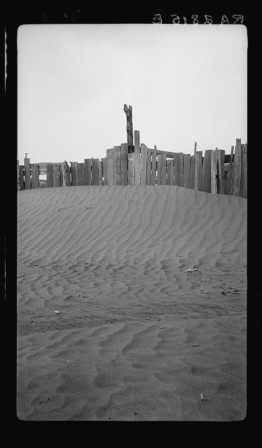 A corral practically buried by drifted dust.