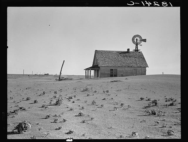 Modest farm house surrounded by dust, nearby power lines