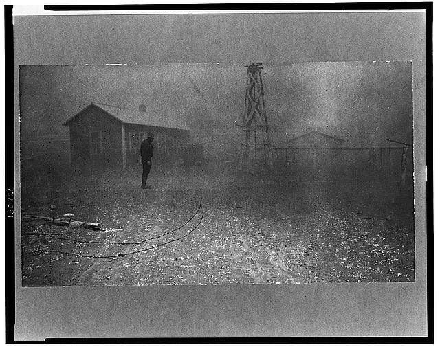Dust storm; man in foreground; buildings in background
