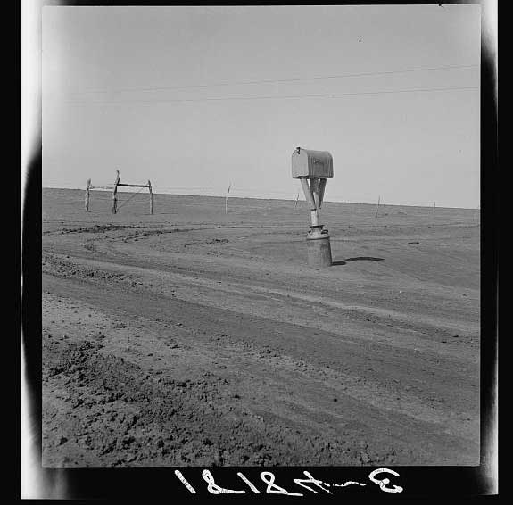 Mailbox in foreground; Dirt road intersection in midground; fence in background